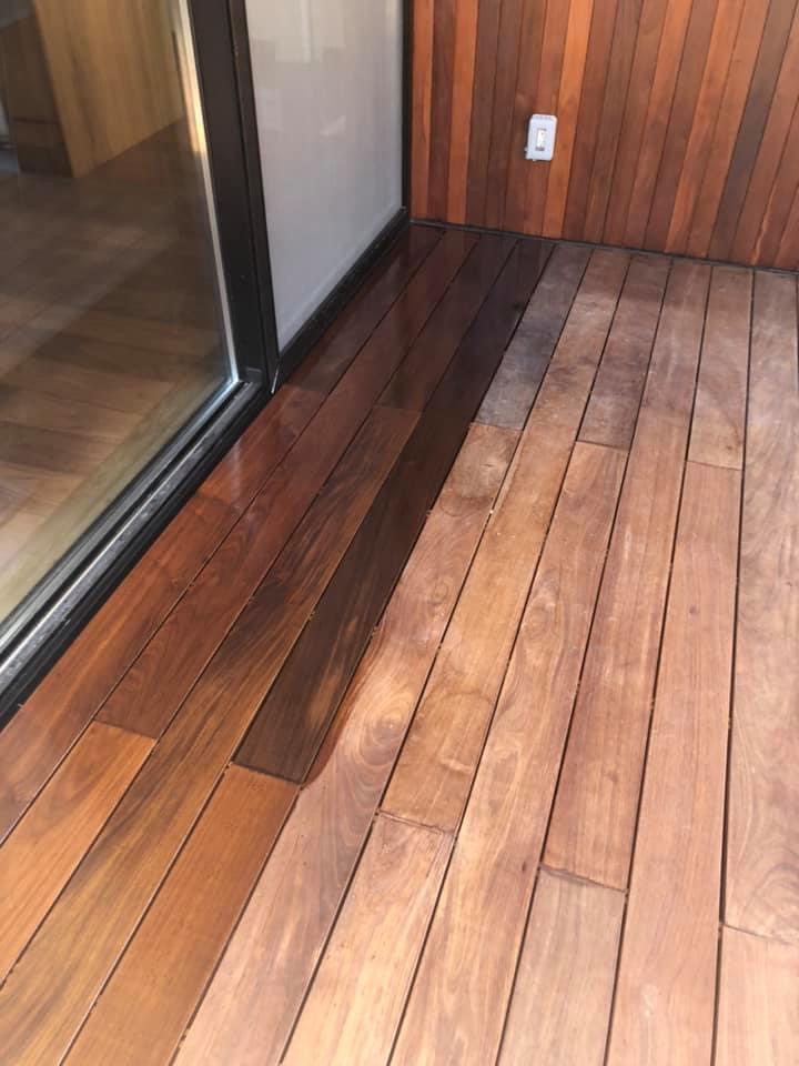 Finished hardwood deck flooring beside a glass door and cedar wall
