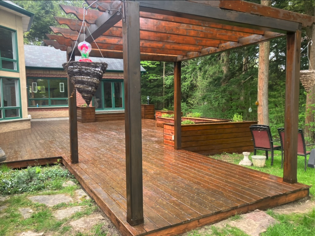 Covered cedar deck and pergola attached to a home in a wooded backyard